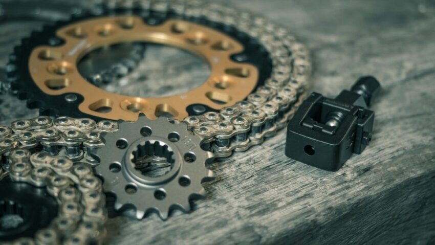 Motorfietsketting met tandwielen en kettingschakelgereedschap op hout