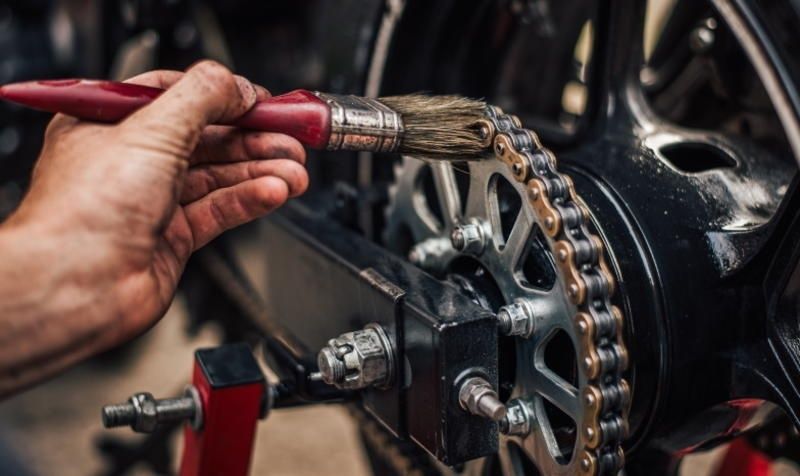 Borsteltje bij de ketting en het tandwiel van een motorfiets