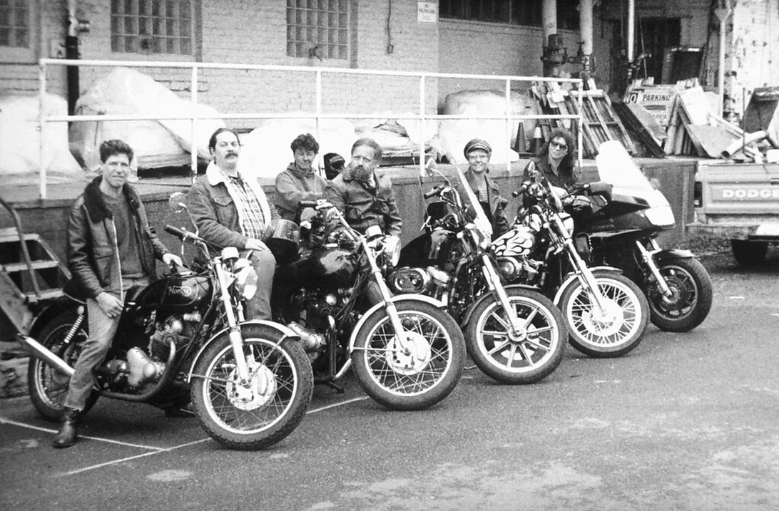 Een groep motorrijders in vintage kleding, met leren jassen en denim, die de klassieke bikercultuur vertegenwoordigen.